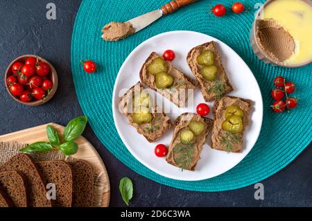 Canapes with chicken liver pate and pickled cucumbers on rye bread. Tasty and healthy appetizer. Top view. Stock Photo