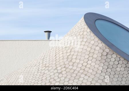 Abstract and modern geometric white stone slab roof against blue sky on a sunny day. Stock Photo
