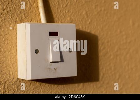 A simple white electrical light switch on a brown wall outdoors in sunshine. Industrial, residential or DIY construction concepts. Stock Photo