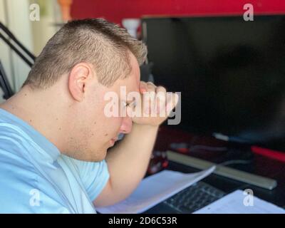 Young man sitting reading a document with engrossed concentration resting his head on his hand as he reads Stock Photo