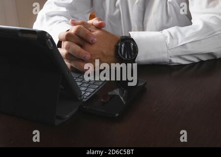 Close-up of the hands of a man in a shirt using smartphone, smart watch and tablet as work tools. Technology usage concept. Horizontal photography Stock Photo