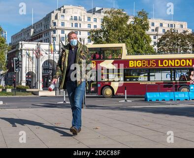 A man on a London street carrying a double bass in a protective