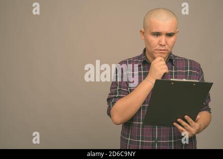 Young bald Asian businessman against gray background Stock Photo