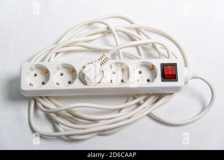 european household white extension cord for 220v with fuse on white textile Stock Photo
