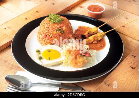 Asian cuisine fried rice with satay, fried shrimp and fried egg Stock Photo