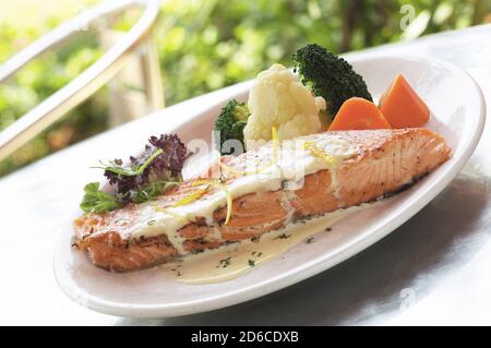 Grilled salmon fish steak with vegetables on restaurant table Stock Photo