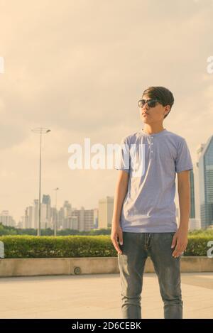 Young Asian teenage boy wearing sunglasses while relaxing at the park Stock Photo