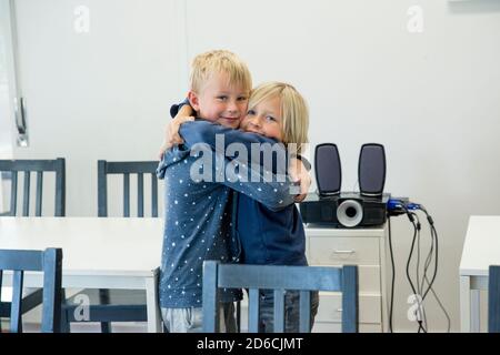 Boys hugging in classroom Stock Photo