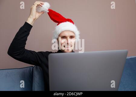 Portrait of smiling handsome man in his home office. Working from home businessman wearing red Santa hat  Adult entrepreneur looking at camera sitting Stock Photo