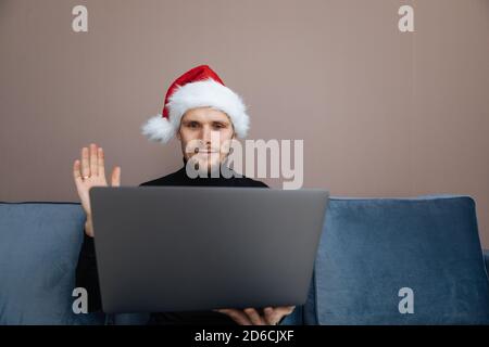 Portrait of smiling handsome man in his home office. Working from home businessman wearing red Santa hat  Adult entrepreneur looking at camera sitting Stock Photo