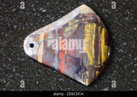 pendant from Jaspillite (Jaspilite) gemstone on black granite background Stock Photo