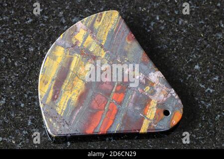 pendant from polished Jaspillite (Jaspilite) stone on black granite background Stock Photo