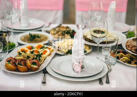 White plates, silver cutlery and glass glasses on a banquet table with a white tablecloth. Stock Photo