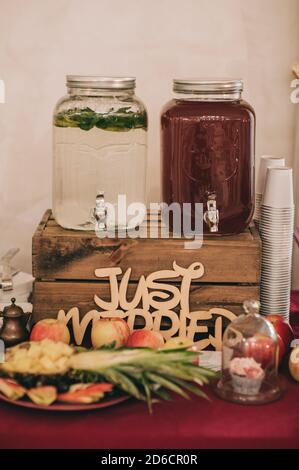 Lemonade and compote on in special glass jars stand on a wooden box on a buffet table. Stock Photo