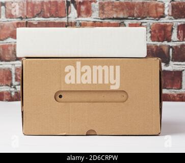 rectangular box made of brown corrugated cardboard on a brown brick wall background, close up Stock Photo