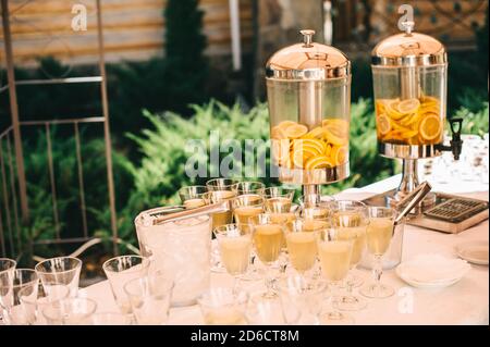 Glass jars of lemonade with sliced citrus fruits on a buffet table. Stock Photo