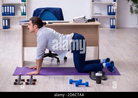 Handsome male employee doing exercises in the office Stock Photo