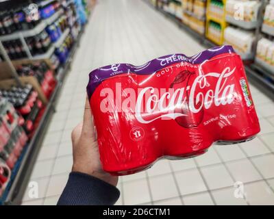 Puilboreau, France - October 14, 2020:Closeup of Man hand buying Coca Cola cherry cans in french market Stock Photo