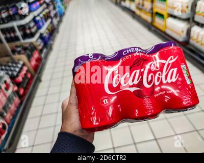 Puilboreau, France - October 14, 2020:Closeup of Man hand buying Coca Cola cherry cans in french market Stock Photo