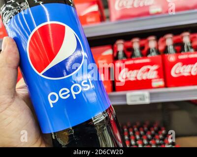 Puilboreau, France - October 14, 2020: Closeup of Man hand buying Pepsi Cola soft drink on supermarket with Coca Cola bottles on background Stock Photo