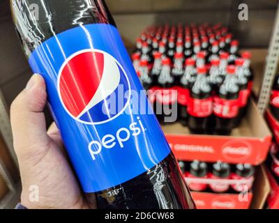 Puilboreau, France - October 14, 2020: Closeup of Man hand buying Pepsi Cola soft drink on supermarket with Coca Cola bottles on background Stock Photo