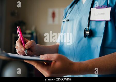 Close up of nurse writing on clipboard preparing for appointment with sick patient while standing in clinic Stock Photo