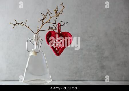 Red crocheted heart on a branch with gray background Stock Photo