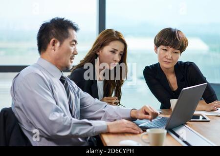 three asian corporate executives man and woman meeting in office using laptop computer Stock Photo