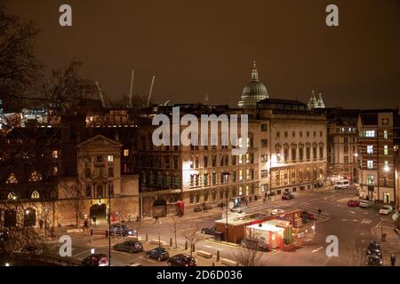 View from on top of a nearby building shows St Bartholemew’s Hospital at Smithfield in the City of London lit by sodium street lights at night with the dome of St Paul’s Cathedral in the middle distance lit against the light-polluted sky. 21 January 2009. Photo: Neil Turner Stock Photo