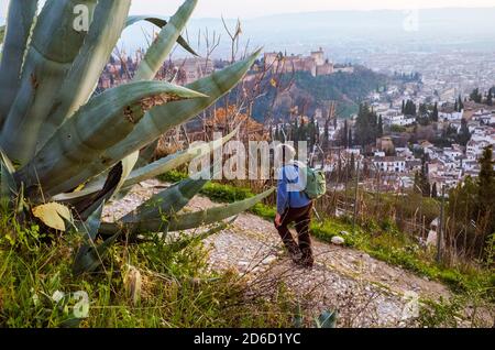 Granada, Spain - January 17th, 2020 : A tourist walks at San Miguel alto viewpoint with the Alhambra palace and Albaicin district in background. Stock Photo