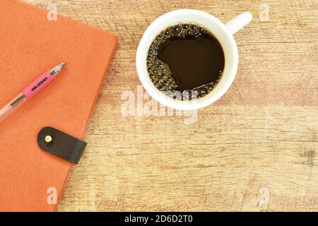 diary book and pen with black coffee cup on wooden table Stock Photo