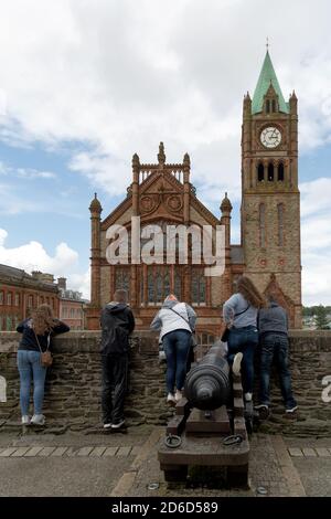 18.07.2019, Derry, Northern Ireland, United Kingdom - Young people lean over the balustrade of the Derry Walls towards the neo-Gothic town hall, The G Stock Photo