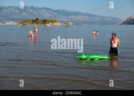 24.06.2020, San Marino, Rab, Primorje-Gorski kotar, Croatia - Man with inflatable rubber crocodile Paradise Beach. 00A200624D105CAROEX.JPG [MODEL RELE Stock Photo