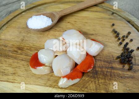 several raw scallops on a cutting board Stock Photo