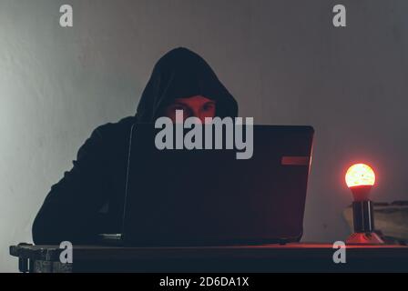 the villain at the laptop in the light of a red lamp, Stock Photo