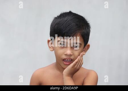 Asian child boy suffering from toothache. Kid touching cheek with hand for tooth pain. Dental problem concept isolated on copy space white background Stock Photo