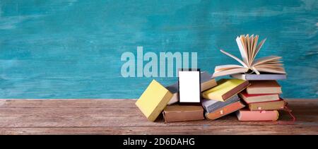 Stack of books and an e-book reader. E- Book, book fair,reading,realaxing,education concept. Free copy space on the screen of the e-book reader. Stock Photo