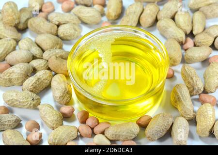 Peanut or groundnut oil in a glass cup with peanuts on the background Stock Photo