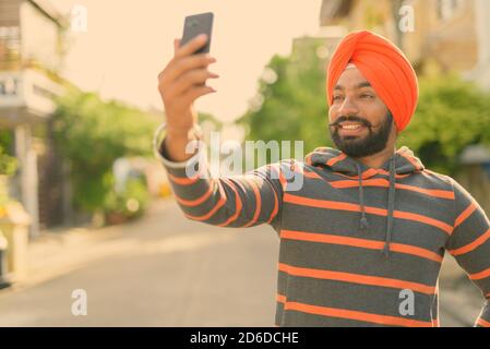 Young handsome Indian Sikh man wearing turban in the streets outdoors Stock Photo