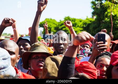 Members of the Economic Freedom Fighters (EFF) and Julius Malema supporters make gestures while standing outside the magistrates court during the protest.A tense standoff between white farmers and Black activists gripped the South African town of Senekal, as two men accused of killing a white farm manager were to appear in court. More than 100 police patrolled the area in front of the courthouse in the Free State province and used barbed wire to separate the rival groups. Stock Photo