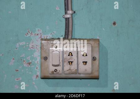 An old electrical switchboard with sockets attached to the painted wall. Aged power switch and output sockets Stock Photo
