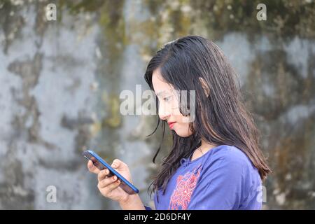 Happy teenage girl using mobile phone. Young lady reading text messages on smartphone screen Stock Photo