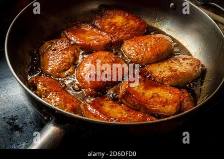 Honey jam glazed BBQ Pork chops frying in large pan Stock Photo