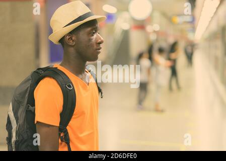 Profile view of young black African tourist man waiting for train in the subway of Bangkok Thailand Stock Photo