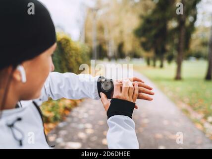 Caucasian female runner checking fitness progress on her smart watch. Woman monitoring a heart rate on her watch outdoors. . Active running people and Stock Photo