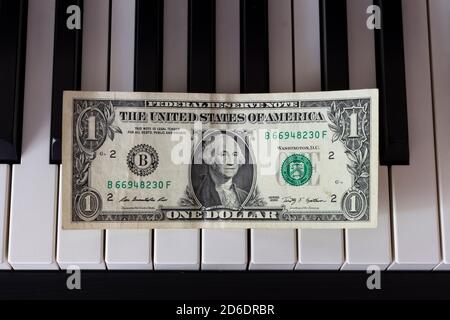 One dollar banknote lying on the piano keys. The dollar as a symbol of global economic management. Stock Photo