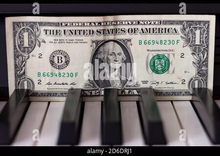 One dollar banknote lying on the piano keys. The dollar as a symbol of global economic management. Stock Photo