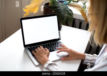 Woman working on her laptop with blank copy space screen. Mock up laptop with womans hands.Back view of business women hands using laptop.Home office Stock Photo
