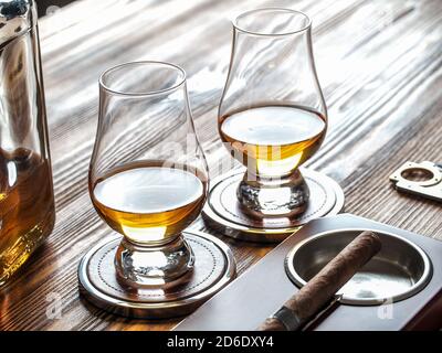 Two dams of whisky in glencairn glasses and a cigar in an ashtray Stock Photo