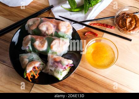 Fresh sliced vietnamese shrimp and vegetable spring rolls with peanut satay dipping and duck sauce Stock Photo